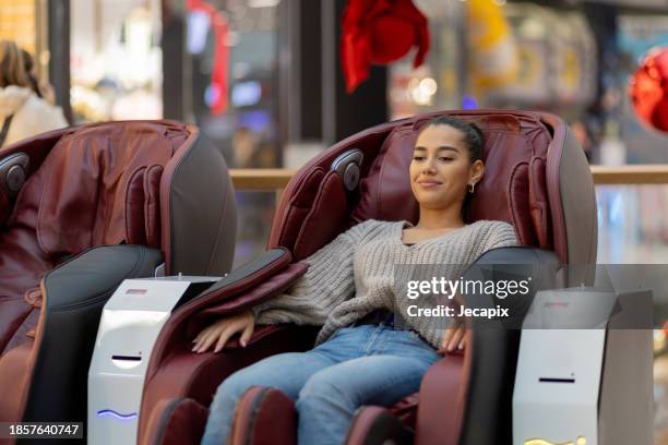 frau entspannen im massagestuhl - massagestuhl stock-fotos und bilder