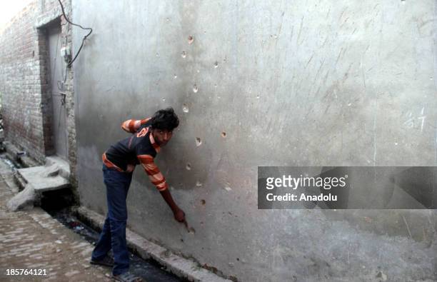 Pakistani villager who lives along the Pakistan-India border in the Charwa of district Sialkot, Pakistan, points the bullet holes on his home...