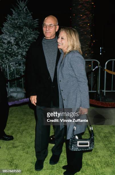 British actor Patrick Stewart, wearing a grey sweater beneath a black jacket with dark grey trousers, and his wife, American television producer...