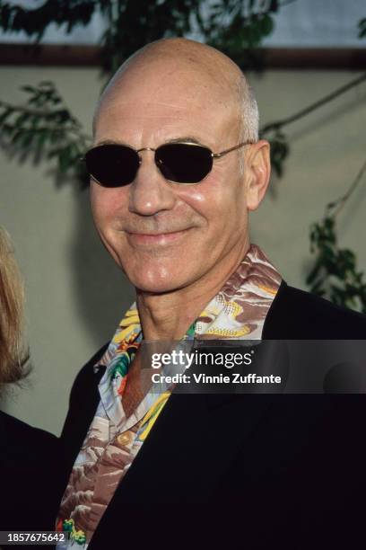 British actor Patrick Stewart, wearing a black jacket over a wide collar Hawaiian shirt with sunglasses, attends the 1996 MTV Movie Awards, held at...