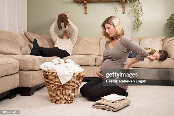 pregnant woman folding laundry, family on couch. - man washing basket child stock pictures, royalty-free photos & images