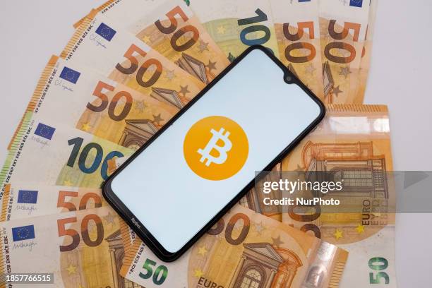 The Bitcoin logo is being displayed on a smartphone screen that is placed on 50 and 100 Euro bills in Athens, Greece, on December 18, 2023.