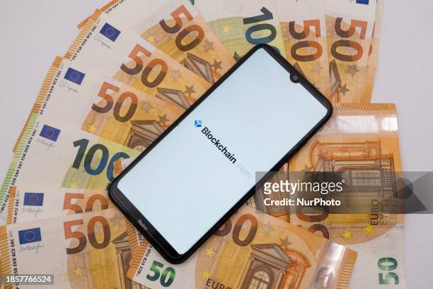 The Blockchain logo is being displayed on a smartphone screen that is placed on 50 and 100 Euro bills in Athens, Greece, on December 18, 2023.