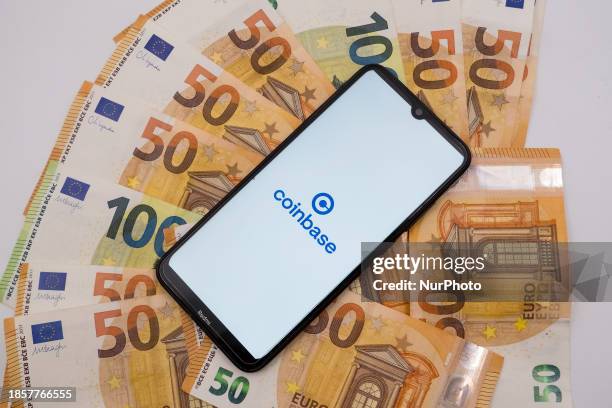 The Coinbase logo is being displayed on a smartphone screen that is placed on 50 and 100 Euro bills in Athens, Greece, on December 18, 2023.