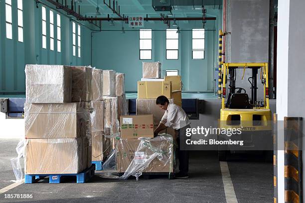 Worker wraps a box in front of a storage area in a logistics center at China Pilot Free Trade Zone's Pudong free trade zone in Shanghai, China, on...