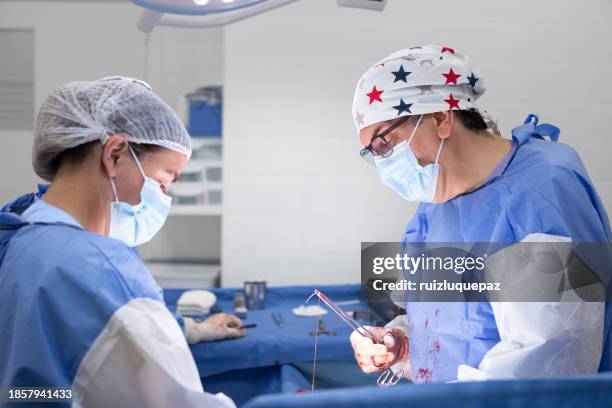 ärzte führen einen kaiserschnitt im operationssaal durch - schnittwunde stock-fotos und bilder