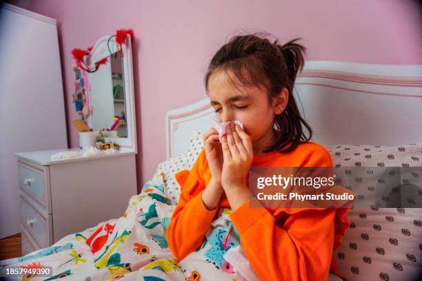 sad kid sitting on bed blowing nose in white napkin - cold virus stock pictures, royalty-free photos & images