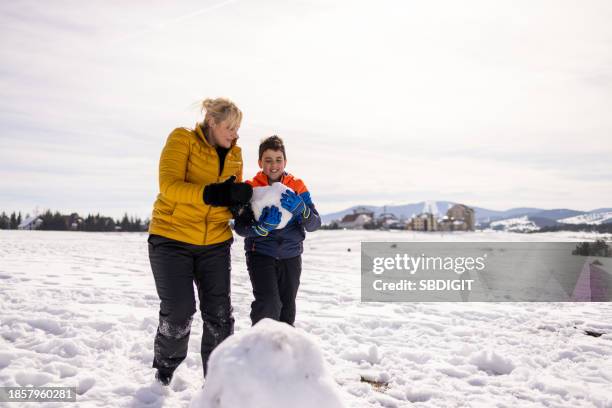 caucasian mother and son making a snowman on the mountain - making a snowman stock pictures, royalty-free photos & images