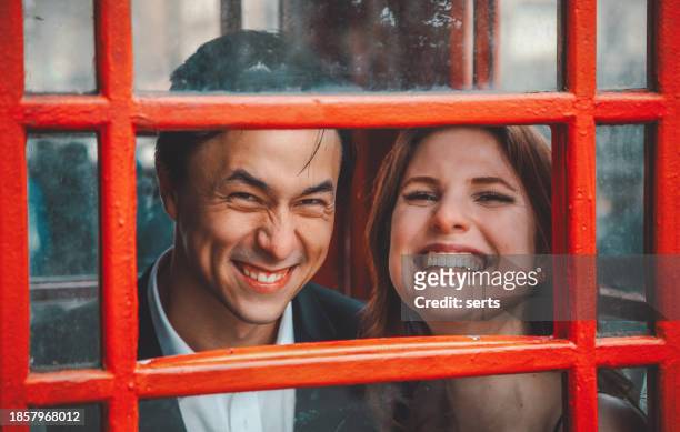 portrait of young and happy couple having fun in london's iconic red telephone booth - tooth bonding stock pictures, royalty-free photos & images
