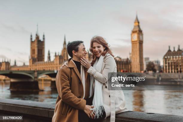 happy and young tourist couple enjoying a romantic getaway in iconic streets of london city, england, united kingdom - couple london stockfoto's en -beelden