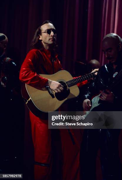 British Pop and Rock musician John Lennon plays acoustic guitar as he performs during the 'Salute To Sir Lew' tribute concert at the Hilton Hotel's...