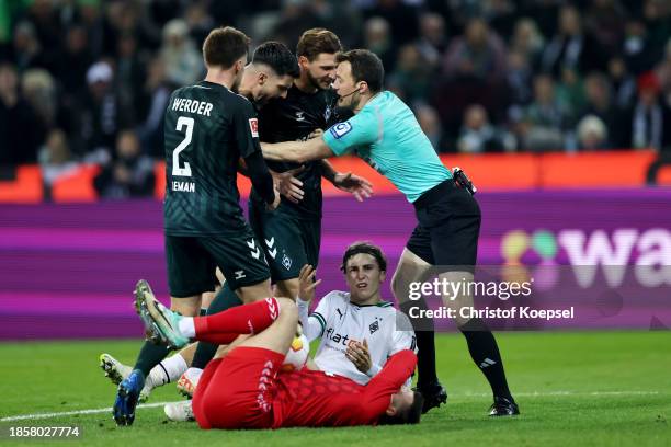 Match Referee, Felix Zwayer holds back Werder Bremen players as Rocco Reitz of Borussia Moenchengladbach reacts during the Bundesliga match between...