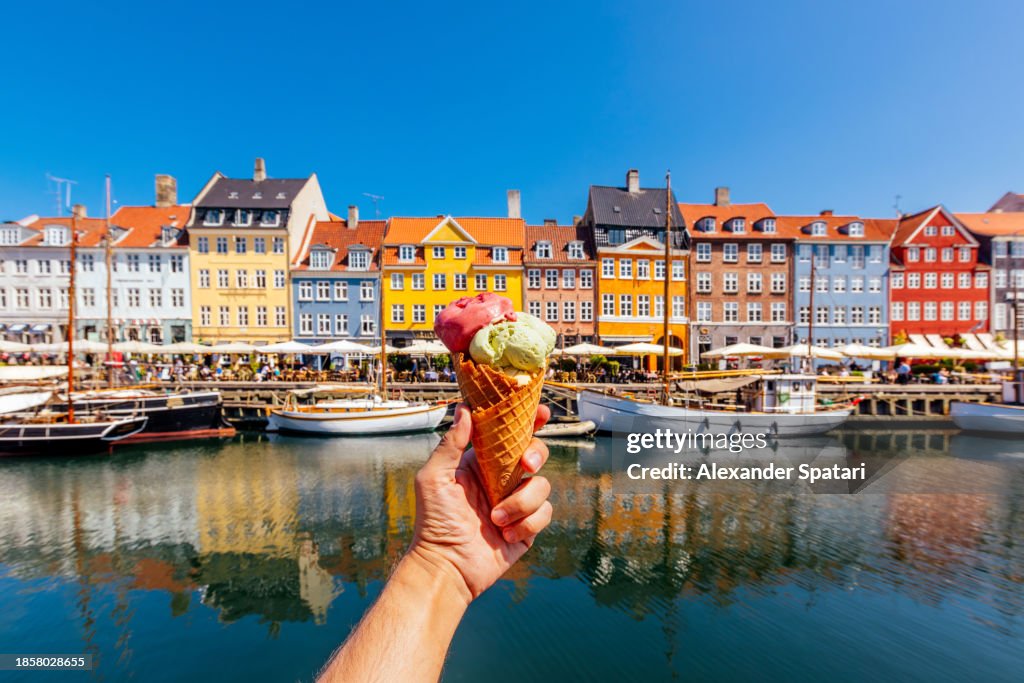 Eating multi-colored ice cream with colourful vibrant houses of Nyhavn harbour in background, Copenhagen, Denmark