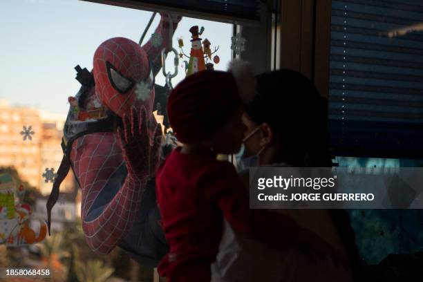 Man dressed as comic-based superhero Spiderman salutes hospitalized children at Materno Infantil hospital in Malaga on December 18, 2023.