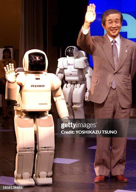 Japan's auto giant Honda Motor President, Hiroyuki Yoshino and the comapny's new humanoid robot ASIMO wave their hands as they react to the audience...