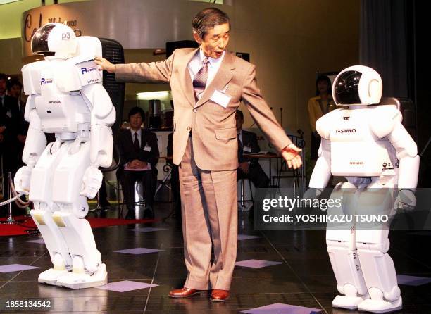 Japan's auto giant Honda Motor President Hiroyuki Yoshino introduces the new humanoid robot ASIMO and previous model of humanoid robot P3 at the...