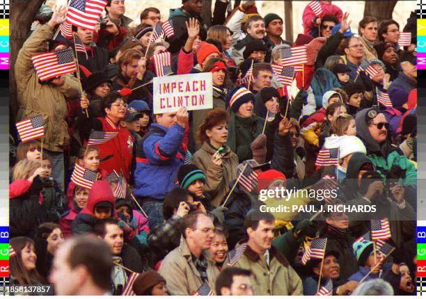 Lone member of the crowd holds up a sign as other parade watchers wave flags during the inaugural parade 20 January in Washington, DC. Earlier, US...