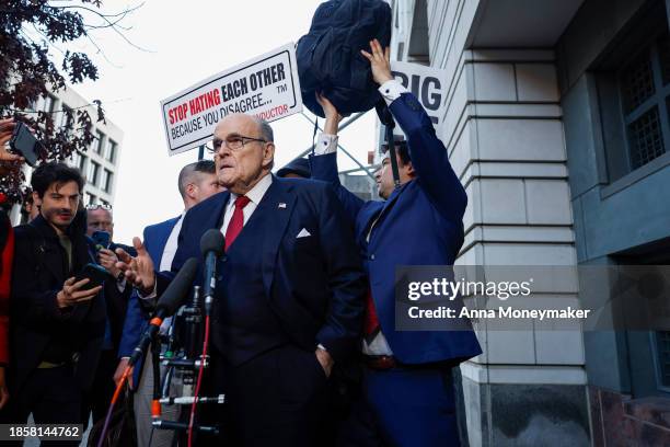 Staff member for Rudy Giuliani, the former personal lawyer for former U.S. President Donald Trump, tries to block a protester's sign as Giuliani...