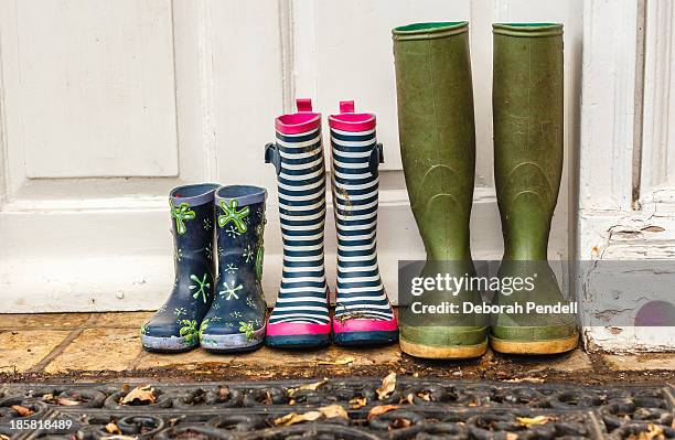 three pairs of muddy wellies at the door - muddy shoe print stock pictures, royalty-free photos & images