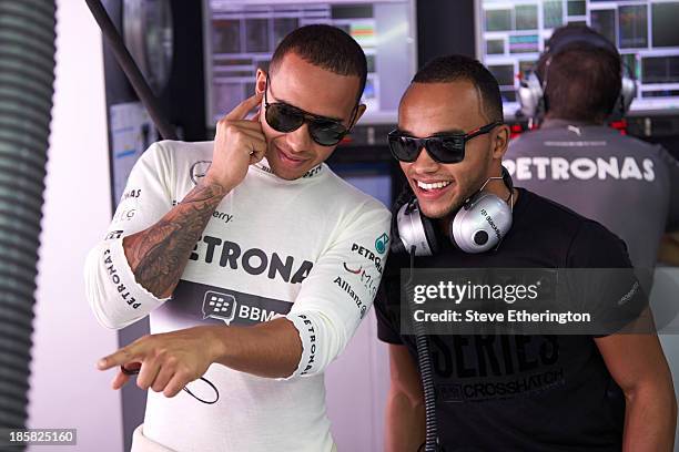 Lewis Hamilton of Great Britain and Mercedes GP talks with his brother Nic Hamilton in his team garage during practice for the Indian Formula One...
