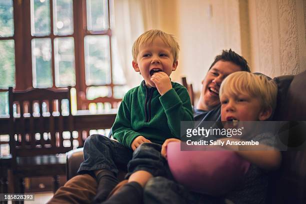 father and sons watching television together - familia viendo television fotografías e imágenes de stock