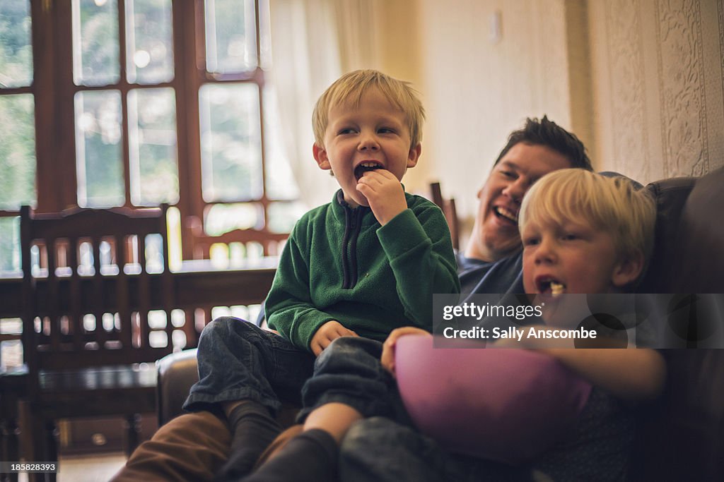 Father and sons watching television together