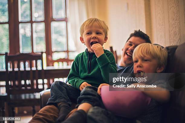 father and sons watching television together - men in white socks 個照片及圖片檔