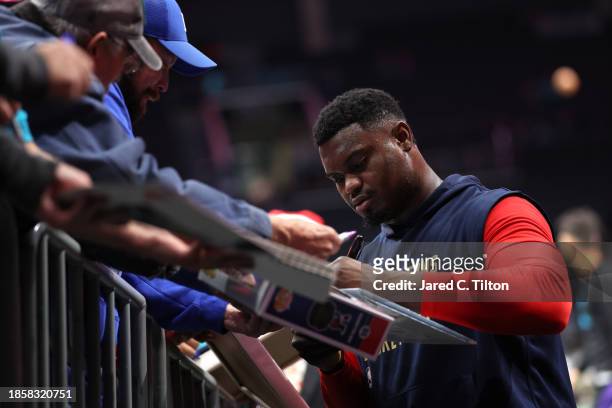 Zion Williamson of the New Orleans Pelicans signs autographs for fans prior to the game against the Charlotte Hornets at Spectrum Center on December...