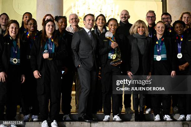 France's President Emmanuel Macron and his wife Brigitte Macron pose with France's handball team's captain Estelle Nze Minko and team members at the...
