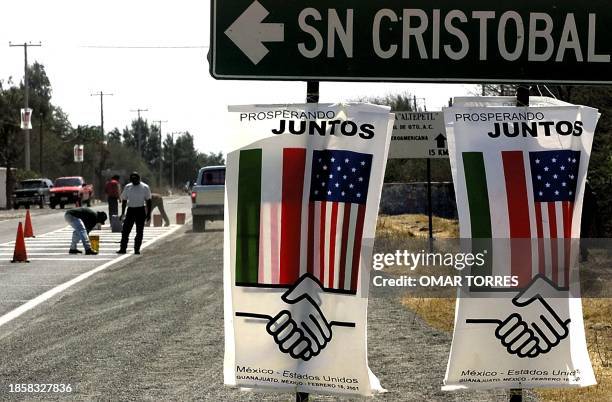 Workers repair this 15 February, 2001 the road to San Cristobal, 30 Kms from Leon, in the Guanajuato State, Mexico, in front of welcome banners, the...