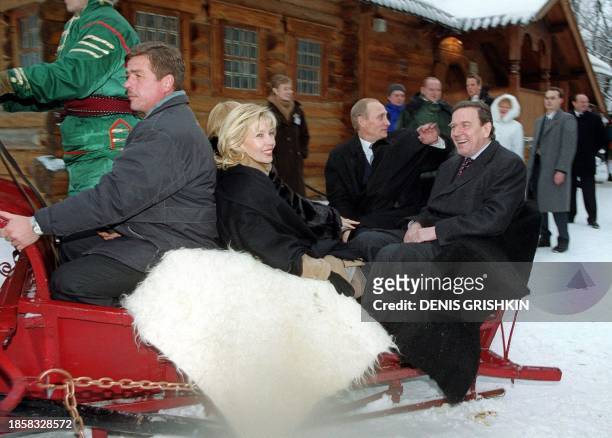 Russian President Vladimir Putin, 2nd from right, waves his hand as he rides around on a troika, the traditional Russian sled pulled by three horses,...