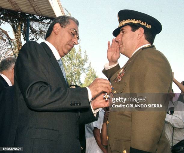 Honduran President Carlos Flores puts the medal "Gran Cruz" of the Armed Forces on the head of Nicaraguan Army, general Javier Carrion, in...