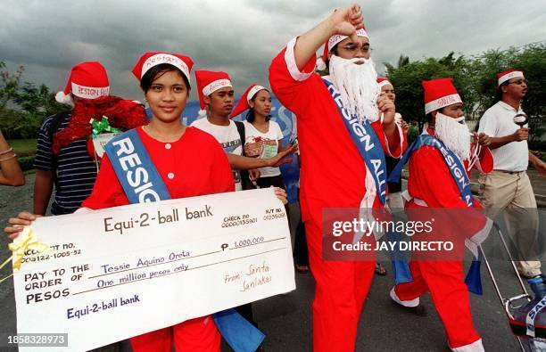 Anti-Estrada protesters, dressed as Santa Claus, march to the Senate carrying a mock up cheque amounting to one million pesos to denounce two...