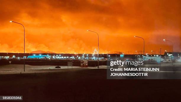 Roads in the town of Keflavik are pictured as smoke billow with lava colouring the night sky orange from an volcanic eruption on the Reykjanes...