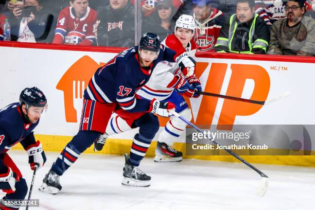 Adam Lowry of the Winnipeg Jets and Cole Caufield of the Montreal Canadiens keep an eye on the play during first period action at the Canada Life...