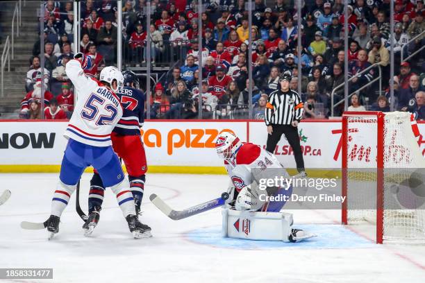 Goaltender Jake Allen of the Montreal Canadiens makes a save as teammate Justin Barron and Nikolaj Ehlers of the Winnipeg Jets look on during first...