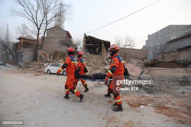 Rescue workers carry a victim after an earthquake in Dahejia, Jishishan County, in northwest China's Gansu province on December 19, 2023. At least...