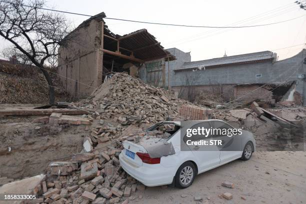 Collapsed buildings and a damaged car are seen after an earthquake in Dahejia, Jishishan County, in northwest China's Gansu province on December 19,...