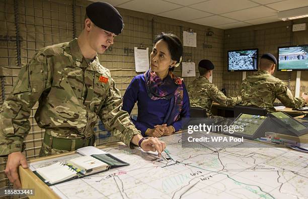 Myanmar's opposition leader Aung San Suu Kyi, wearing a remembrance poppy, listens to Officer Cadet Ed Clarke in a simulation of a Forward Operating...