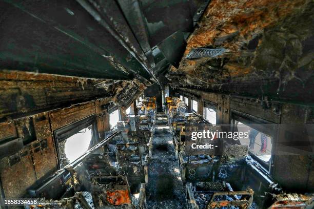 Graphic content / A general view of a burned out railway coach after it allegedly set on fire by opposition activists, in Dhaka on December 19, 2023....
