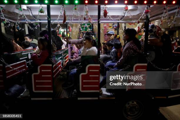 Group of people is boarding the new Christmas Train that is circulating in the streets of Santiago Zapotitlan Tlahuac, Mexico City, as part of the...