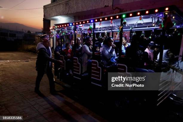 Group of people is boarding the new Christmas Train that is circulating in the streets of Santiago Zapotitlan Tlahuac, Mexico City, as part of the...