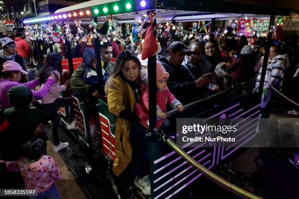 Group of people is boarding the new Christmas Train that is circulating in the streets of Santiago Zapotitlan Tlahuac, Mexico City, as part of the...