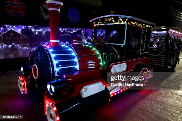 Group of people is boarding the new Christmas Train that is circulating in the streets of Santiago Zapotitlan Tlahuac, Mexico City, as part of the...