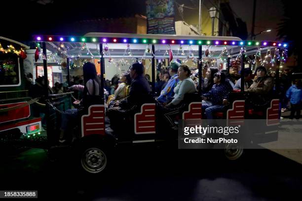 Group of people is boarding the new Christmas Train that is circulating in the streets of Santiago Zapotitlan Tlahuac, Mexico City, as part of the...