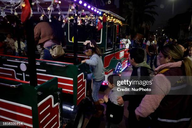 Group of people is boarding the new Christmas Train that is circulating in the streets of Santiago Zapotitlan Tlahuac, Mexico City, as part of the...