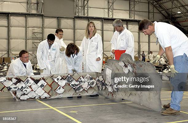 In this NASA photo, NASA crash investigators examine debris from the Space Shuttle Columbia March 18, 2003 at Kennedy Space Center, Florida. NASA is...