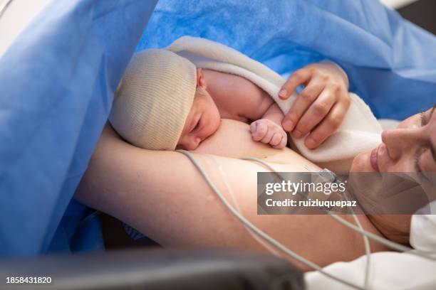mother breastfeeds her newborn baby after a cesarean section - childbirth stock pictures, royalty-free photos & images