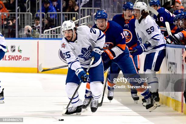 Conor Timmins of the Toronto Maple Leafs is pursued by Julien Gauthier of the New York Islanders at UBS Arena on December 11, 2023 in Elmont, New...