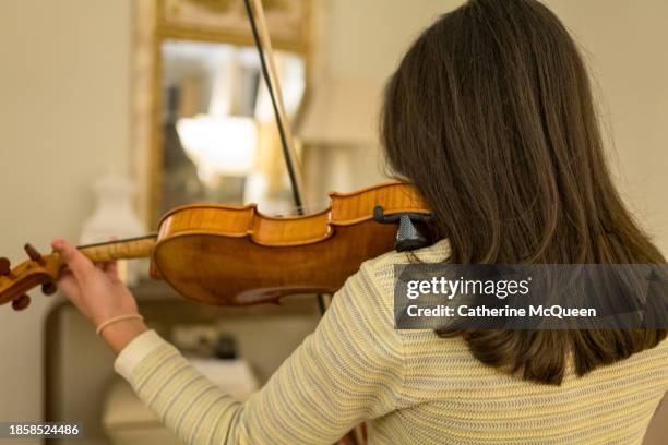 multiracial young woman prepares for violin performance - classical orchestral music stock pictures, royalty-free photos & images